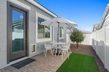 A patio with a table and chairs and a white umbrella.